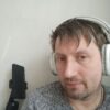 Серые наушники и сосредоточенный взгляд на говорящего, короткие волосы и светлый фон — мотив «Богатый папа, бедный папа» от Роберта Кийосаки