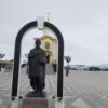 Памятник «Медный всадник» в Парке 70-летия Победы, Салехард: статуя из серого гранита, арка с надписями и золотой купол часовни.