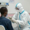 A hospital scene in Goma showing a doctor in full protective gear attending to a patient with Ebola fever, with a clear view of the hospital environment and medical equipment, no text or symbols