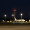A nighttime scene at Volgograd Airport on May 31, showing a dark sky, illuminated runway lights turned off, a control tower with red warning lights, several aircraft parked on the tarmac with their lights dimmed, and a subtle sense of a flight ban without any visible signage or text