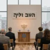 A solemn commemorative ceremony at the Moscow Center of Contemporary Judaism, featuring a modest modern building with a discreet Hebrew sign, a diverse group of people in modest attire gathered in a hall, a central table with a lit menorah and traditional Jewish symbols, soft warm lighting, and a view of the Moscow skyline through large windows, conveying respect and remembrance