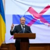 A Ukrainian government official standing at a podium, gesturing passionately, with a Ukrainian flag prominently displayed behind them. In the background, a large, partially torn Russian flag is being pulled away or crossed out, symbolizing a rejection of the Russian language. The scene conveys a paradoxical tension without any visible text or symbols.