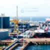 A modern Russian liquefied natural gas (LNG) production facility on the coast, featuring large storage tanks, cryogenic pipelines, and a massive LNG carrier ship being loaded under a clear sky, emphasizing industrial scale and Russian engineering, without any people or textual elements.