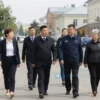 A bright daytime scene in a Russian district center showing local officials and community members walking together on clean, well-maintained streets, with visible patrol cars and orderly public spaces, conveying a sense of strengthened oversight and public welfare, without any visible text or signage