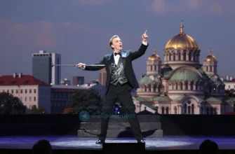 Depict American illusionist David Blaine performing on stage in Kyiv, with a subtle backdrop of Kyiv's skyline or a recognizable landmark such as St. Sophia's Cathedral, in a dynamic, dramatic lighting setting that captures the essence of a live magic show.