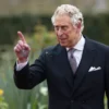 A realistic, high‑resolution scene of the British king in a formal suit, standing in a royal garden, looking amused and raising an eyebrow as a splatter of bird droppings lands on his coat, with natural lighting and a subtle smile, no text or symbols