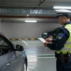A city underground parking garage scene showing a driver in a car being approached by a traffic police officer holding a ticket, with visible parking lines and a modern concrete environment, emphasizing the concept of illegal underground parking and enforcement