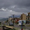 A photorealistic scene of a Chilean coastal city during a magnitude 6.7 earthquake, showing cracked streets, tilted buildings, dust and debris clouds, and the distant Andes mountains under a dramatic sky