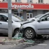 A car colliding with a street pole near the Aquamolla shopping center in Ulyanovsk, showing the impact scene with debris, broken glass, and a damaged vehicle, in a realistic urban setting.