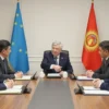 A formal meeting between the head of Chuvashia and a delegation of Kyrgyz officials in a modern conference room, shaking hands over a round table with documents, with subtle background elements like the flags of Chuvashia and Kyrgyzstan displayed on stands, warm lighting, realistic expressions, and a professional atmosphere