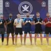 A group of proud grappling athletes from Orlov, standing on a competition mat, holding up their nine medals and celebrating their victory. The scene shows a diverse team in sportswear, with a backdrop of a championship banner and a trophy shelf, capturing the excitement and achievement of the grappling championship.