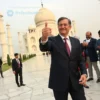 A scene at the Taj Mahal showing a Western male politician in a suit taking a selfie, while a group of Iranian onlookers nearby are laughing and making humorous gestures, capturing the cultural contrast without any text or symbols