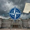A dramatic scene showing the NATO emblem cracking apart like a shattered glass, with a solemn parliament building in the background and a symbolic law document floating nearby, all under a tense, stormy sky to convey the threat of division within the alliance