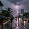 A bustling city street under a heavy tropical downpour with dramatic thunderstorm, bright lightning illuminating wet asphalt, reflections on windows, people with umbrellas, skyscrapers in the background, dramatic sky