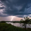 A dramatic, photorealistic scene of the Volgograd region under heavy rain, dark thunderclouds, bright lightning, and strong wind blowing trees and grass, with a river reflecting the stormy sky, all in a realistic landscape view