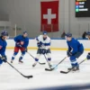A dynamic hockey match scene on an indoor rink in Switzerland, featuring Czech and Slovenian teams in full gear, with players in action—Czech players in blue jerseys, Slovenian players in white and blue, a Swiss flag in the background, and a scoreboard showing a close score, all captured in a realistic, high-resolution style