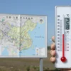 A bright sunny day in the Komi region with a large digital thermometer indicating 28°C, a map of Komi in the background, and clear blue sky.