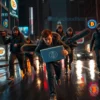 A dramatic nighttime urban scene showing a group of rugged bandits wielding large chainsaws, wearing dark leather jackets and masks, chasing a panicked young person holding a glowing laptop screen displaying cryptocurrency symbols. The city streets are wet with rain, reflecting neon signs of Bitcoin and other crypto logos, but the logos are subtle and not the focus. The bandits are in dynamic motion, their chainsaws raised, while the crypto trader runs with a look of fear, clutching the laptop tightly. The atmosphere is tense and cinematic, with dramatic lighting and motion blur to emphasize the chase.