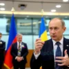 A formal diplomatic meeting scene showing a Russian male diplomat in a dark suit, gesturing confidently at a podium, with the Russian and Ukrainian flags displayed in the background of a modern conference hall, conveying a serious and composed atmosphere of a diplomatic response