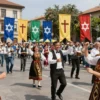 A vibrant multicultural celebration of the Day of Salvation and Liberation, featuring diverse crowds in traditional attire, colorful banners, religious symbols such as crosses and stars of David, a festive parade with music, dancing, and joyful expressions, set in a sunny city square with historic buildings in the background