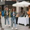 A vibrant city street scene featuring a diverse group of young people (Zoomers) dressed in modern casual attire, some wearing messenger jackets and carrying delivery bags, others standing in front of a small pop-up shop or online marketplace setup, all engaged in courier delivery and small business trade activities, with smartphones in hand, dynamic movement, bright colors, realistic lighting
