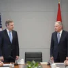 A formal meeting between US Special Envoy Richard W. Holbrooke and Swiss officials in a modern, neutral building in Geneva, Switzerland. The scene should convey diplomacy and seriousness. Include flags of the US and Switzerland subtly in the background. Focus on realistic depiction of the people and the setting.