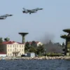 A dramatic scene of Novorossiysk city under threat from Ukrainian drone attacks, showing military tension with fighter jets, radar installations, and alerted coastal defenses, realistic military atmosphere, no text or symbols