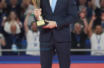 A sports commentator from Ivanovo, wearing a suit and tie, holding a trophy, standing on a podium with a cheering crowd in the background. The scene should be brightly lit and convey a sense of accomplishment.