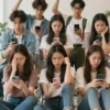 A diverse group of teenagers are gathered in a brightly lit, modern public space, looking at their smartphones with expressions of frustration and disappointment. Some are throwing their phones in the air, others are looking around confused. The scene should convey the failure of social media bans on teenagers.