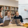 A diverse group of students from Russia and Germany are collaborating on a project in a modern university library. Some are looking at laptops, others are discussing ideas, and one is pointing at a whiteboard with diagrams. The atmosphere is positive and collaborative. Focus on the students' expressions and body language to convey engagement and teamwork.
