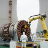 A realistic depiction of the Fukushima nuclear power plant's second reactor during fuel extraction, featuring workers in full protective suits and a robotic arm or crane removing a fuel assembly from the reactor core, with the reactor building, containment structure, and safety equipment clearly visible, emphasizing industrial safety and technical precision.
