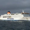 A large passenger ship, MV Hondius, anchored in open sea under a dark, overcast sky, with no visible signs of life or activity on deck, surrounded by calm but ominous waters, conveying a sense of isolation and danger