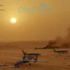 A photorealistic image depicting the aftermath of a drone strike over a desert landscape. Several damaged Iranian drones are scattered across the sand, with debris and smoke visible in the distance. A US military aircraft is flying overhead, silhouetted against the setting sun.