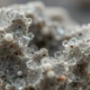 A microscopic view of a rock sample showing the process of solidification, with visible crystal structures forming. Focus on the intricate details of the cooling process and the development of different mineral phases.