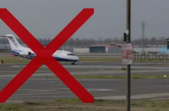 A realistic depiction of Volgograd airport with a grounded plane on the tarmac, a large red X overlaying the runway to indicate closure, and a closed sign hanging from a pole, all without any text or lettering