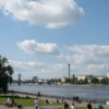 A calm, sunny day in Volgograd. Blue sky with fluffy white clouds. A peaceful cityscape with recognizable landmarks like the Volga River and bridges. People are enjoying outdoor activities – walking in the park, relaxing by the river. The overall mood is serene and pleasant, reflecting the absence of magnetic storms.