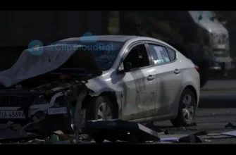 A photo-realistic image depicting the aftermath of a car accident in Donetsk. Focus on the damaged car, with visible impact marks and debris scattered around. Include a грузовик (truck) in the background, partially obscured. The scene should convey a sense of tragedy and loss.