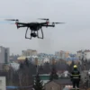 A drone crash in the sky above Voronezh city. Debris is falling. City buildings are visible in the background. Emergency services are responding.