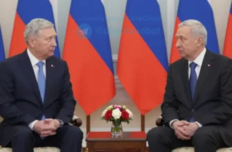 A diplomatic meeting between US and Russian officials. The scene should depict a formal setting, possibly a conference room in a government building. Both officials should be present, engaged in conversation. The atmosphere should be serious and professional.