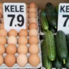 A market stall in the Volgograd region featuring fresh eggs and cucumbers with price tags that show a decrease in egg prices and an increase in cucumber prices, depicted without any text or numbers, highlighting the contrast between the two produce items and their price signs