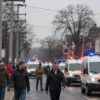 A wide shot depicting a street in the Zaporizhzhia region of Ukraine. Power lines are visibly down, with some sparking. People are walking around, some looking concerned. Emergency vehicles (ambulances, fire trucks) are present, some with flashing lights. The overall atmosphere should convey the aftermath of a power outage and the ongoing efforts to restore power.