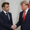 A serious-looking Emmanuel Macron and Donald Trump shaking hands in a neutral setting, symbolizing diplomatic discussions. Focus on their faces and body language to convey the gravity of the situation.