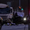 A photorealistic image depicting the aftermath of a traffic accident involving a KAMAZ truck and a police car in Yekaterinburg. The scene should show damaged vehicles, emergency lights flashing, and police officers investigating the scene. Focus on realism and detail.