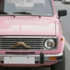 A pink UAZ car with a distinctive mustache, parked on a sunny street. The car is the main focus, and the mustache is clearly visible. The background should be slightly blurred to emphasize the car.