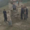 A family of four (parents and two children) standing in front of a modest house in Bosnia and Herzegovina. The family should appear concerned and slightly distressed. The house should be simple, possibly with a stone facade. The background should show a slightly overcast day with rolling hills in the distance.