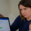 A concerned mother holding her children's hands, looking at a laptop screen displaying a fake Gosuslugi (State Services) login page with a warning sign. The background shows a blurred image of a family home. Focus on conveying worry and security.