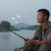 A Chinese fisherman looking at another fisherman with a mysterious, knowing expression, surrounded by subtle digital code fragments floating in the air like fish scales, symbolizing hidden connections and trust, in a serene riverside setting at dusk