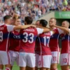 A photo-realistic image of the Russian national football team celebrating a goal during a FIFA World Cup match. The team is wearing their national jerseys, and the background shows a stadium filled with cheering fans. Focus on the emotion and excitement of the moment.