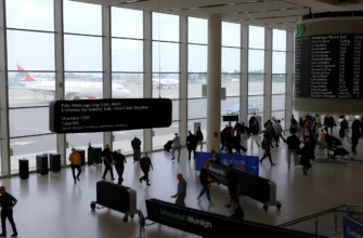 A busy Munich airport terminal with airplanes on the runway, travelers moving through the terminal, and a large digital display showing flight information, captured in a realistic style