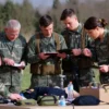 A group of veterans of the Special Military Operation (SVO) in Orenburg are participating in a skills competition. They are demonstrating various skills, such as first aid, equipment maintenance, and tactical exercises. The scene should be outdoors, with a backdrop of the Orenburg landscape. Focus on camaraderie and skill demonstration.